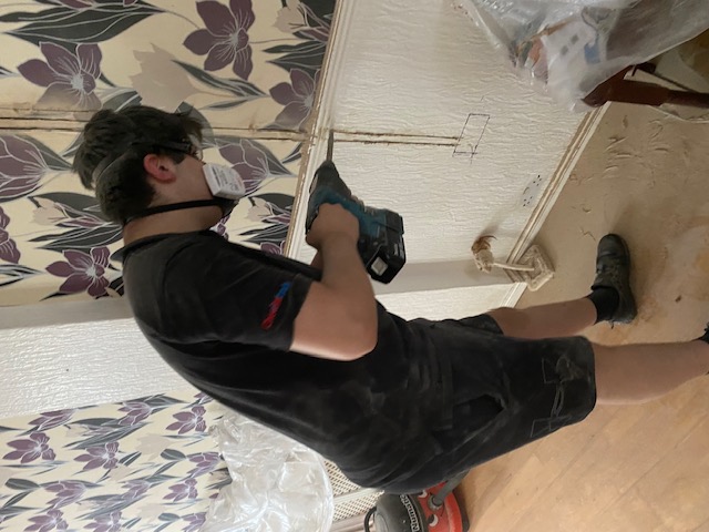 Engineer drilling for cable routing in residential property