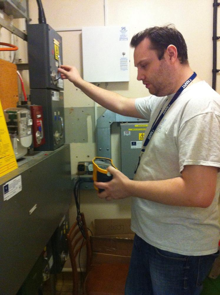 Steve Green, founder of 24/7 Electrical Ltd, testing a commercial electrical panel with a multimeter